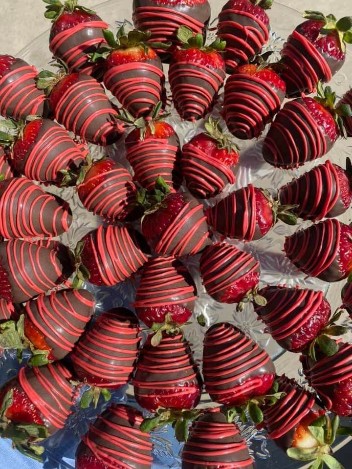Hand-dipped chocolate strawberries with red drizzle arranged on a crystal platter